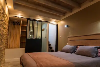 a bedroom with a large bed with a wooden headboard at Les gîtes du Canal du midi - Gîte Loft'Oten in Avignonet-de-Lauragais