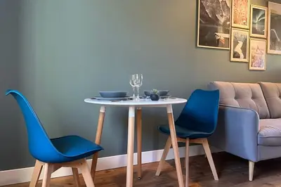 a table with two blue chairs and a couch at Les gîtes du Canal du midi - Gîte Loft'Oten in Avignonet-de-Lauragais