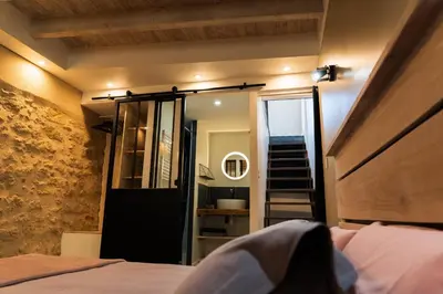a bedroom with a bed and a mirror and a staircase at Les gîtes du Canal du midi - Gîte Loft'Oten in Avignonet-de-Lauragais