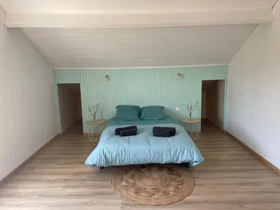 a bedroom with a bed with blue sheets and two tables at Maison La Vielmuroise in Vielmur-sur-Agout