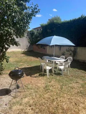 a grill and a table with chairs and an umbrella at Maison La Vielmuroise in Vielmur-sur-Agout