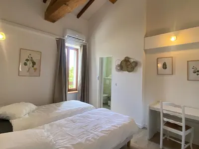 a bedroom with two beds and a desk and a window at T3 bord canal du midi, piscine in Homps