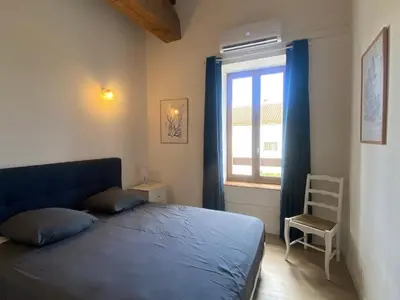 a bedroom with a blue bed and a window at T3 bord canal du midi, piscine in Homps