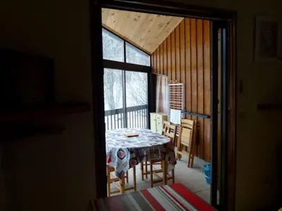 a table in a room with a view of a snow covered yard at Logement dans chalet à la montagne in Montferrier