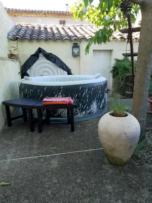 a bench and a bath tub next to a table at Maison isivier in Magrie