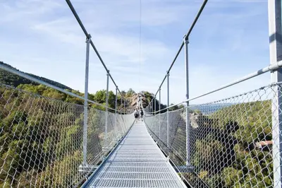 a suspension bridge over a canyon with a person on it at Villas du Golf Domaine Royal Green in Pont-de-Larn