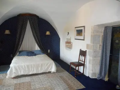 a bedroom with a bed and a chair at Logis de La Meschaussée, dans donjon du XIe siècle in Canet d'Aude