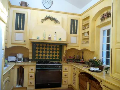 a kitchen with wooden cabinets and a black stove top oven at Logis de La Meschaussée, dans donjon du XIe siècle in Canet d'Aude