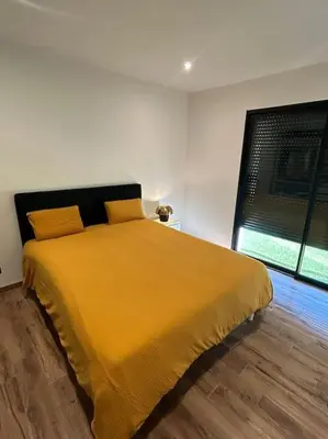 a yellow bed in a white room with a window at Villa Catalya moderne piscine chauffée in Carcassonne