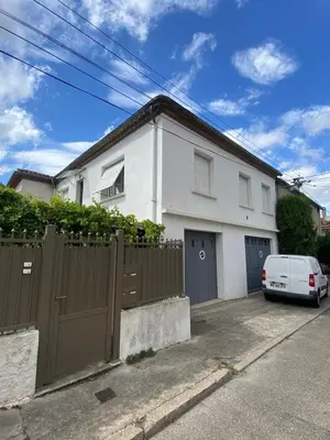a white house with a fence and a car parked in front at Maison de charme avec jardin in Carcassonne
