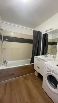 a bathroom with a tub and a washing machine at Appartement T2 avec piscine in Mirepoix