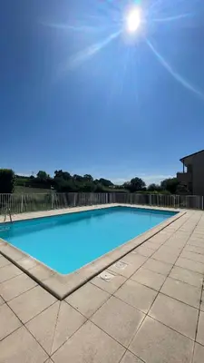 a large blue swimming pool with the sun in the sky at Appartement T2 avec piscine in Mirepoix
