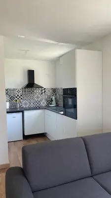 a living room with a gray couch in a kitchen at Appartement T2 avec piscine in Mirepoix