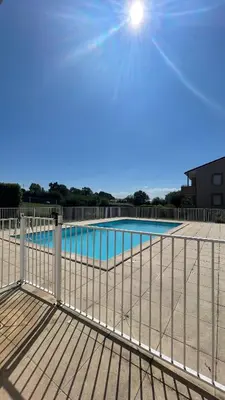 a fence next to a swimming pool with the sun at Appartement T2 avec piscine in Mirepoix