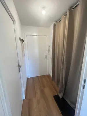 a hallway with a white door and a wooden floor at Appartement T2 avec piscine in Mirepoix