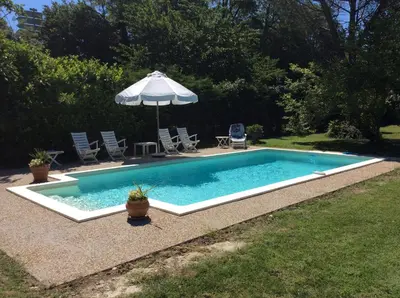 a swimming pool with an umbrella and some chairs and an umbrella at Maison du Breilh in Mirepoix