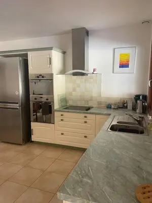 a kitchen with white cabinets and a stainless steel refrigerator at Quillan Villa with Pool in Quillan