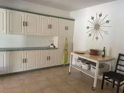 a kitchen with white cabinets and a table and a clock at Quillan Villa with Pool in Quillan