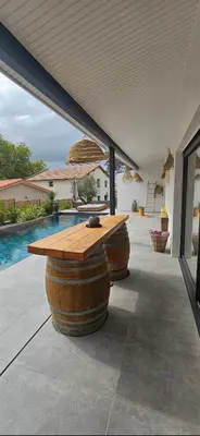 a patio with a wooden table and two wine barrels at Loft & spa d'Autan in Villefranche-de-Lauragais