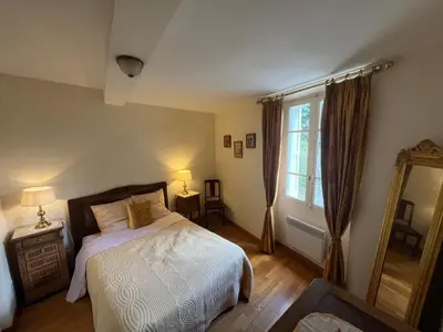 a bedroom with a bed and a large window at Maison de village in Saint-Hilaire