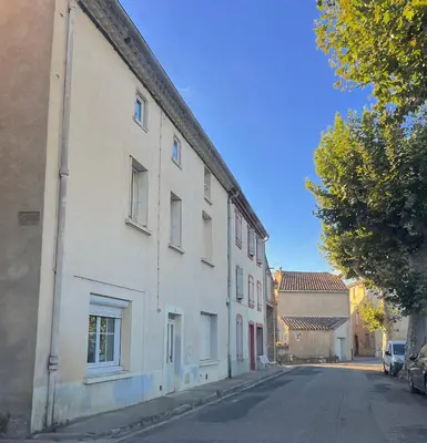 a white building on the side of a street at Maison de village in Saint-Hilaire