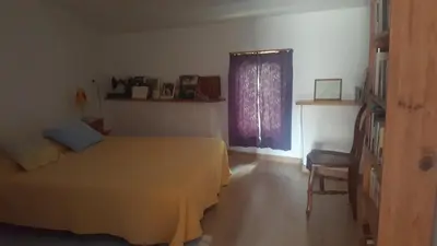 a bedroom with a bed and a window and a chair at Maison de village in Saint-Hilaire