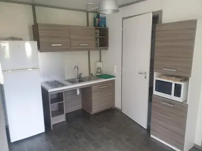 a small kitchen with a sink and a refrigerator at CAMPING MUNICIPAL LA SAPINETTE in Quillan