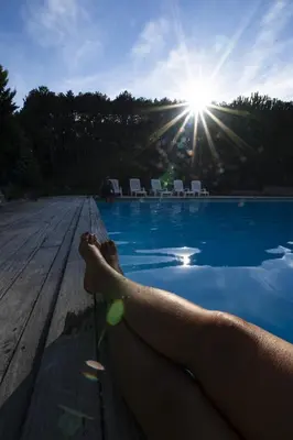 a person laying on the edge of a swimming pool at CAMPING MUNICIPAL LA SAPINETTE in Quillan