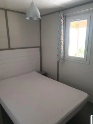 a bedroom with a white bed and a window at CAMPING MUNICIPAL LA SAPINETTE in Quillan