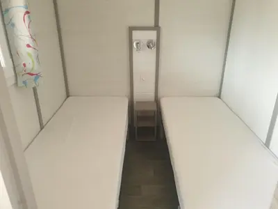 two beds in a small room with a hallway at CAMPING MUNICIPAL LA SAPINETTE in Quillan