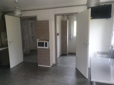 a room with a kitchen with a microwave on a counter at CAMPING MUNICIPAL LA SAPINETTE in Quillan
