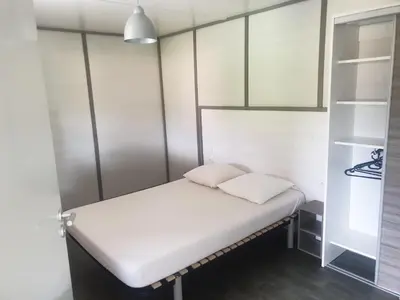 a small room with a bed and a closet at CAMPING MUNICIPAL LA SAPINETTE in Quillan