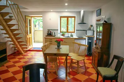 a kitchen with a table and chairs and a staircase at LA MAISONNETTE DU POTIER in Caunes-Minervois