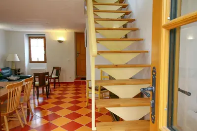 a wooden staircase in a living room with a checkered floor at LA MAISONNETTE DU POTIER in Caunes-Minervois