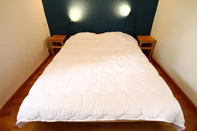 a white bed in a small room with two tables at LA MAISONNETTE DU POTIER in Caunes-Minervois