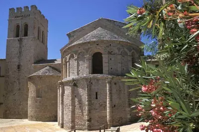 a large stone building with a tower and a church at LA MAISONNETTE DU POTIER in Caunes-Minervois