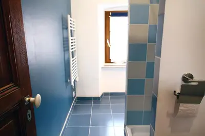 a bathroom with a blue tile floor and a door at LA MAISONNETTE DU POTIER in Caunes-Minervois