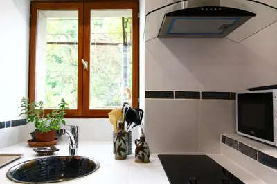 a kitchen with a sink and a window and a tv at LA MAISONNETTE DU POTIER in Caunes-Minervois