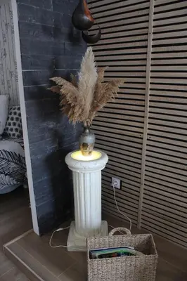 a vase with feathers on a pedestal in a room at Gîte La Tchoupetta in Peyriac-de-Mer