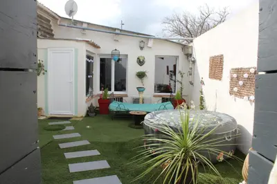 a garden with a patio with a bench and a table at Gîte La Tchoupetta in Peyriac-de-Mer