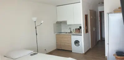 a room with a bed and a kitchen with a washing machine at Studio Gruissan Vue Port in Gruissan