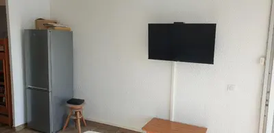a television hanging on a wall next to a refrigerator at Studio Gruissan Vue Port in Gruissan
