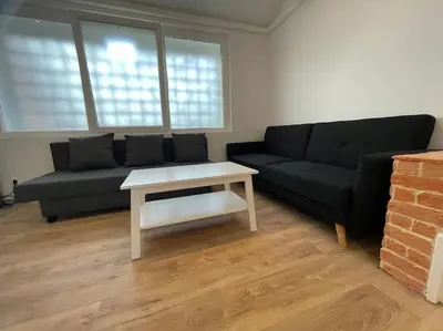 a living room with a black couch and a table at Magnifique appartement Narbonne in Narbonne