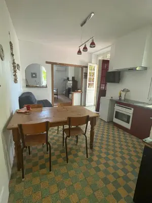 a kitchen and living room with a wooden table and chairs at Du côté de chez nous in Cuxac-dʼAude