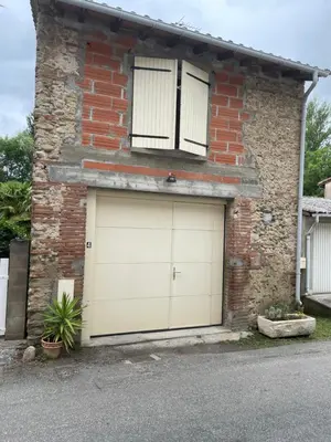 a brick house with two garage doors on it at Appart T2 au Vernet d'Ariège avec jardin privatif in Le Vernet