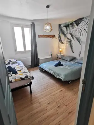 a bedroom with two beds and a chair in it at Les remparts de Caroline, au pied de La Cité. in Carcassonne