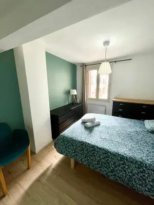 a bedroom with a bed and a chair and a window at Les remparts de Caroline, au pied de La Cité. in Carcassonne