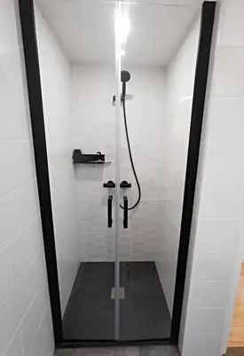 a shower with a glass door in a bathroom at Les remparts de Caroline, au pied de La Cité. in Carcassonne