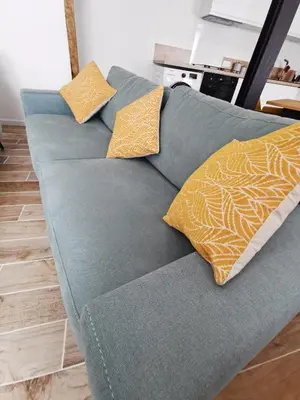 a blue couch with two yellow pillows on it at Les remparts de Caroline, au pied de La Cité. in Carcassonne
