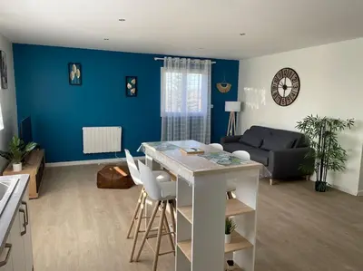 a kitchen and living room with a blue wall at Chez ERIC in Villeneuve-du-Paréage